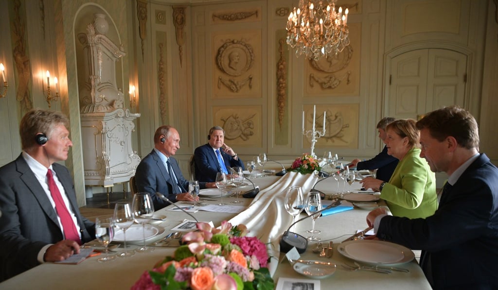Putin and Merkel with aides during Putin’s working visit to Germany on Saturday. Photo: EPA-EFE