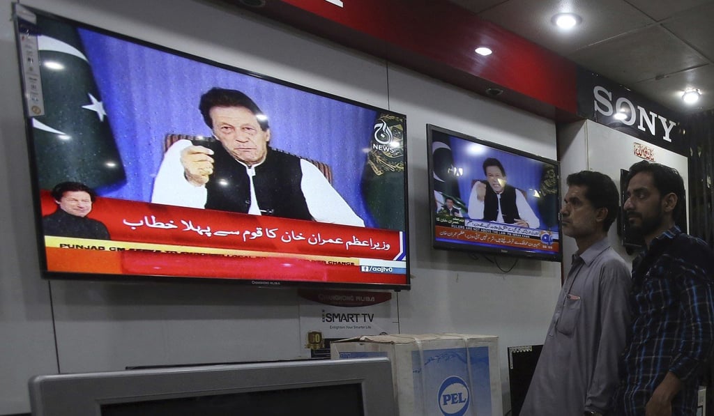 Customers in an electronics shop in Karachi listen to Khan’s speech. Photo: AP Customers in an electronics shop in Karachi listen to Khan’s speech. Photo: AP
