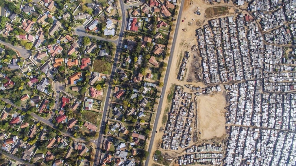 Luxury homes – some with swimming pools – in the middle-class, tree-lined suburb of Bloubosrand (left), alongside the cramped shacks of the informal settlement of Kya Sands, to the north west of Johannesburg, in South Africa.