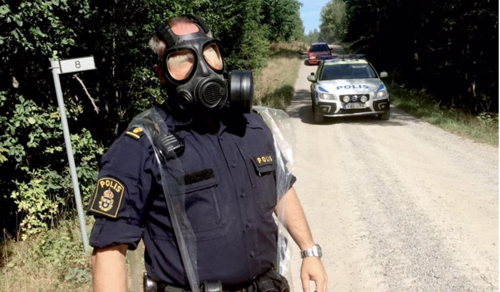 A police officer in a protective mask near the place where the Swedish Air Force fighter jet crashed outside Ronneby, Sweden on August 21, 2018. Photo: EPA