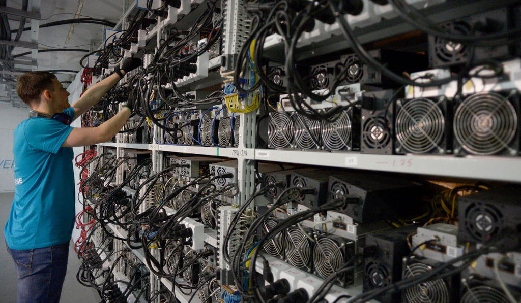 An employee inspects machines for the production of bitcoins and litecoins at the Kriptoyunivers mining centre in Kirishi, Russia. Photo: Agence France-Presse