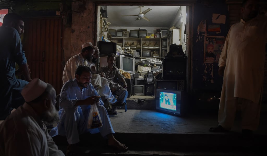 Pakistani men outside a shop watching a televised speech by Prime Minister Imran Khan. Photo: AFP