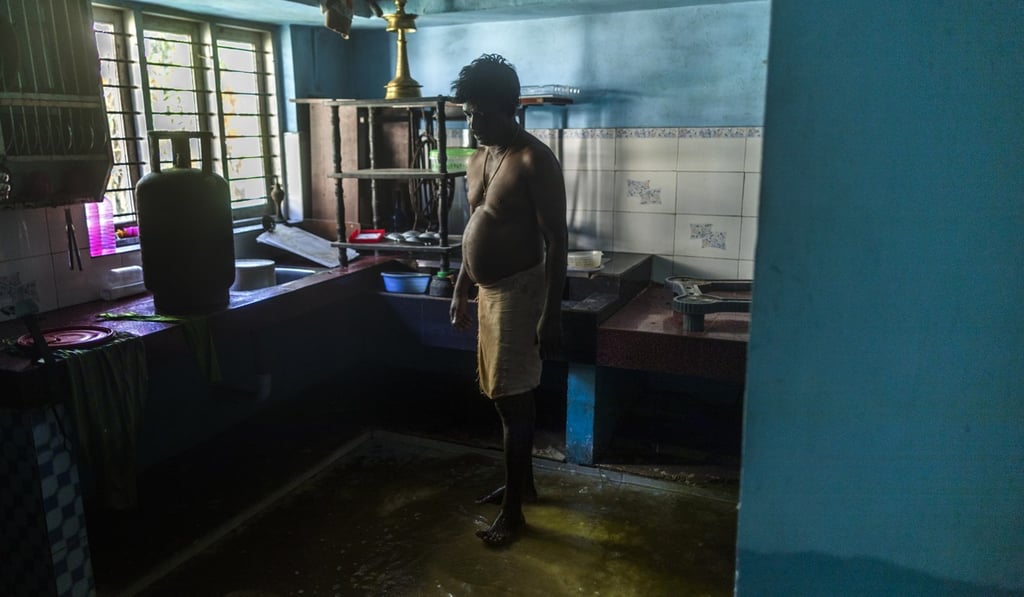 A man stands in the kitchen of a home partially submerged in floodwaters in Kerala, India on Thursday. Local media reports warned that snakes may be hiding in cupboards or under carpets. Photo: Bloomberg