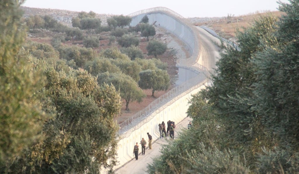 This file photograph taken on October 8, 2017, in the Syrian village of Aqrabat, in the Harem district of Idlib province, on the border with Turkey, shows rebel fighters walking next to the three-metre high fortification, built by the Turkish government along its border with Syria. Photo: Agence France-Presse This file photograph taken on October 8, 2017, in the Syrian village of Aqrabat, in the Harem district of Idlib province, on the border with Turkey, shows rebel fighters walking next to the three-metre high fortification, built by the Turkish government along its border with Syria. Photo: Agence France-Presse