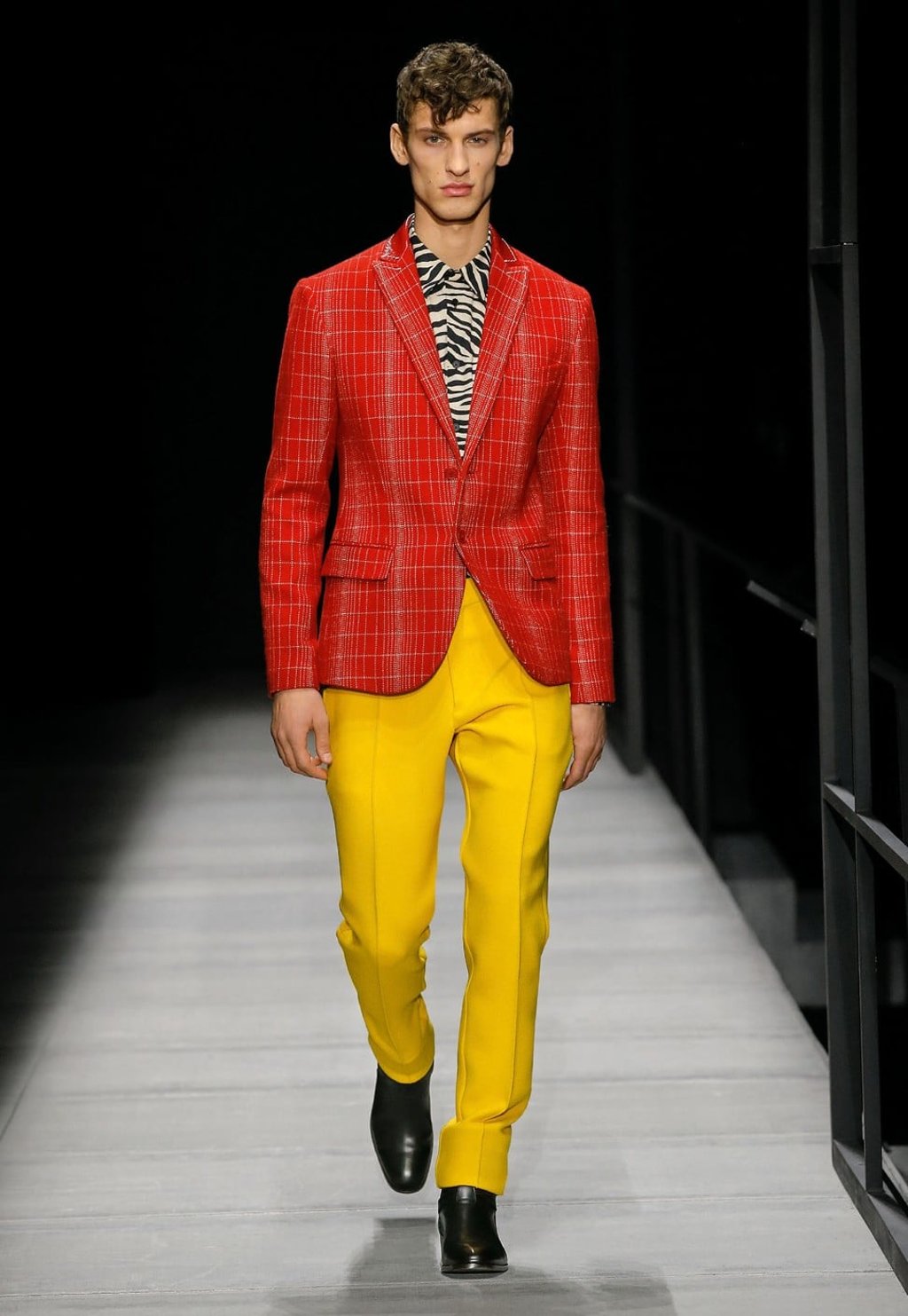 A sharp orange jacket with a cube pattern is paired with a print shirt and bright yellow trousers for a bold look at Bottega Veneta’s autumn/winter men’s collection show.
