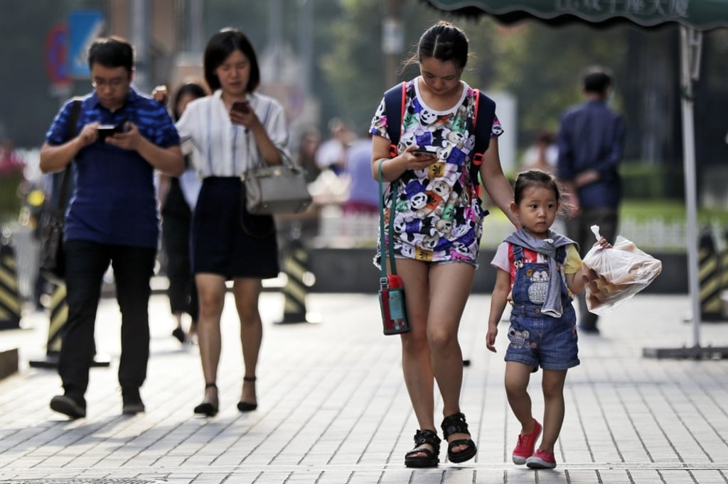 Pedestrians view their smartphones as they walk along a pavement in Beijing. China has one of the world’s largest mobile phone market. Photo: AP