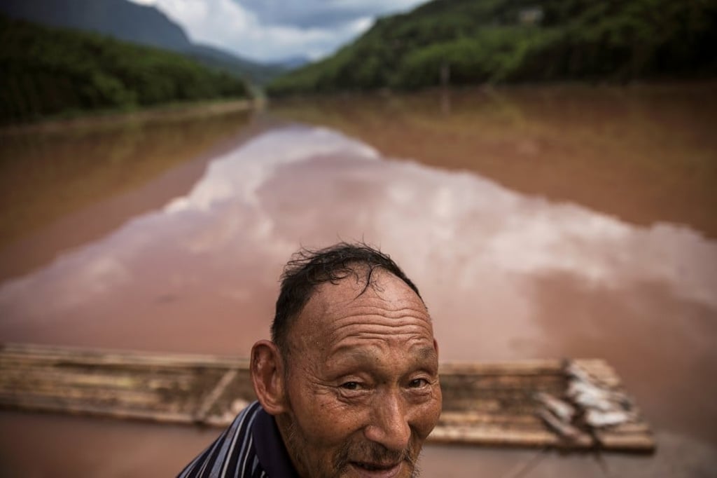 A 70-year-old farmer, surnamed Zhang, stands near his catch on the Zhougong river in Sichuan.