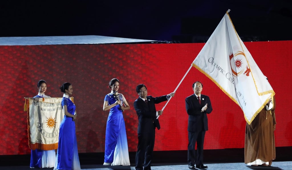 A representative from China waves the Olympic Council of Asia flag after it was handed over by Indonesia. Photo: Reuters