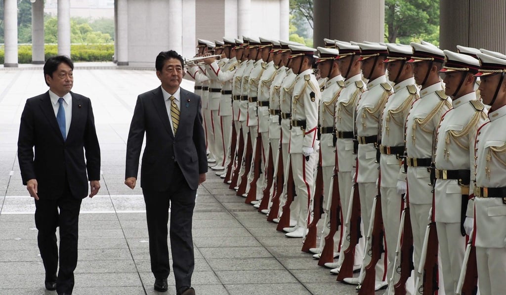 Defence Minister Itsunori Onodera, left, and Abe review an honour guard at the Defence Ministry on Monday. Photo: AFP Defence Minister Itsunori Onodera, left, and Abe review an honour guard at the Defence Ministry on Monday. Photo: AFP
