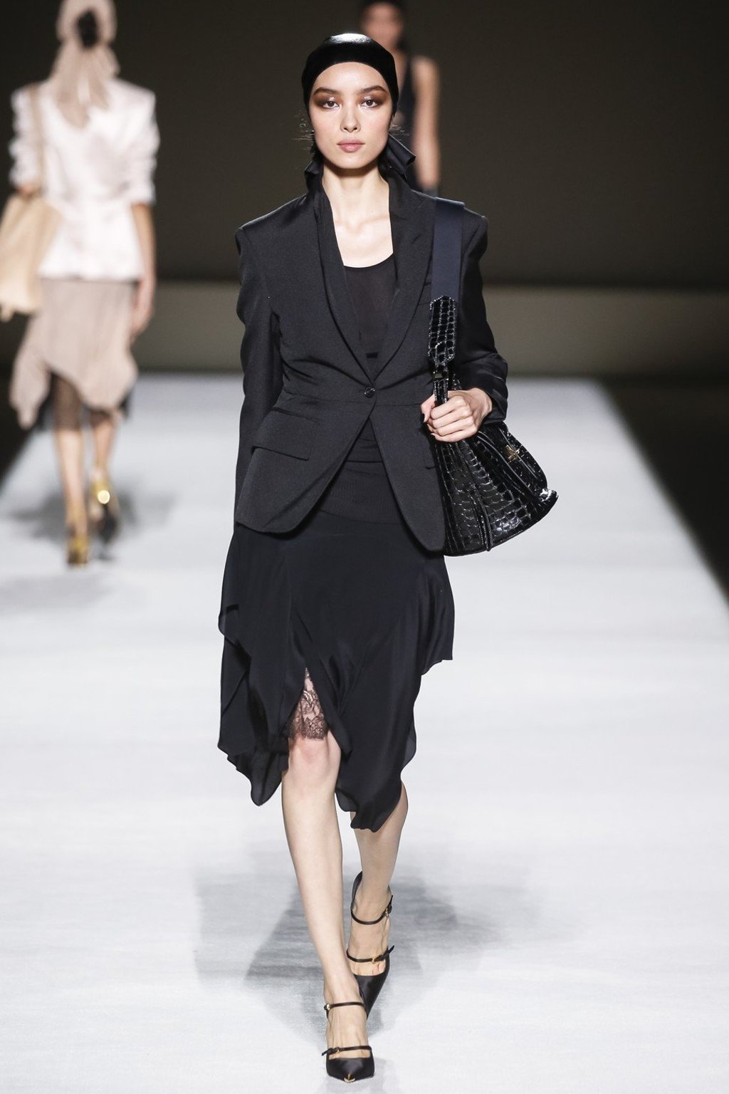 Chinese model Feifei Sun strides the runway in an all-black attire with a sexy metallic eye shadow makeup.