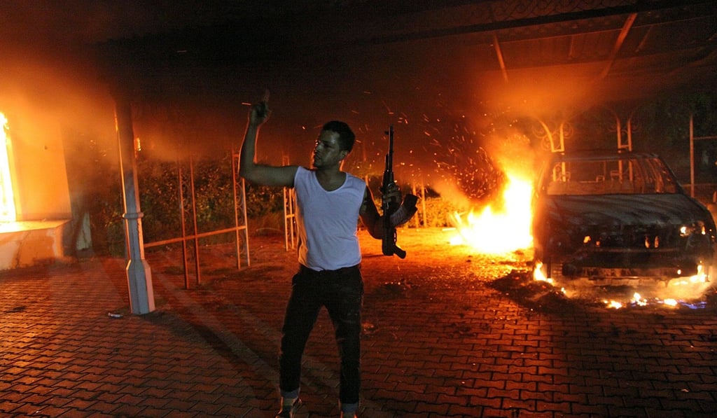 This file photo taken on September 11, 2012 shows an armed man waving his rifle as buildings and cars are engulfed in flames after being set on fire inside the US consulate compound in Benghazi. Photo: Agence France-Presse