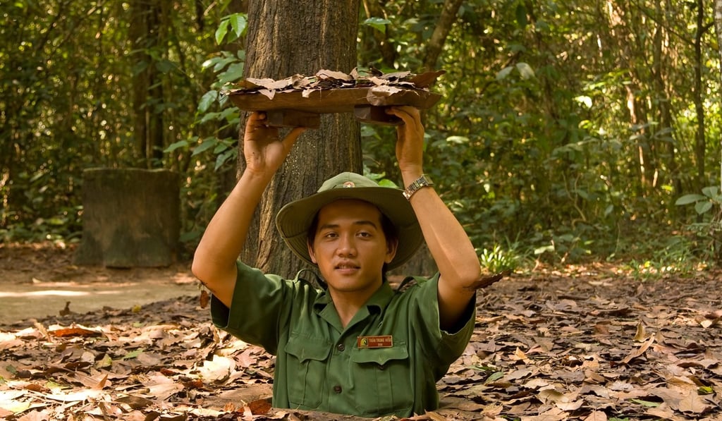 A soldier shows the entrance to the Cu Chi tunnel system near Ho Chi Minh City, in Vietnam. Picture: Alamy