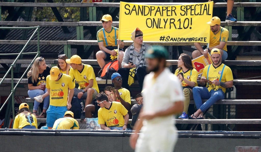 South African fans hold a banner and wear masks as they mock Australia cricket players during day one of the fourth test match after news of the scandal broke. Photo: AFP