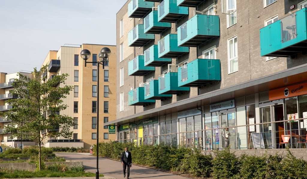 A pedestrian walks past a parade of shops below residential properties in the Barking Riverside housing development in the Barking and Dagenham borough of London. Photo: Bloomberg