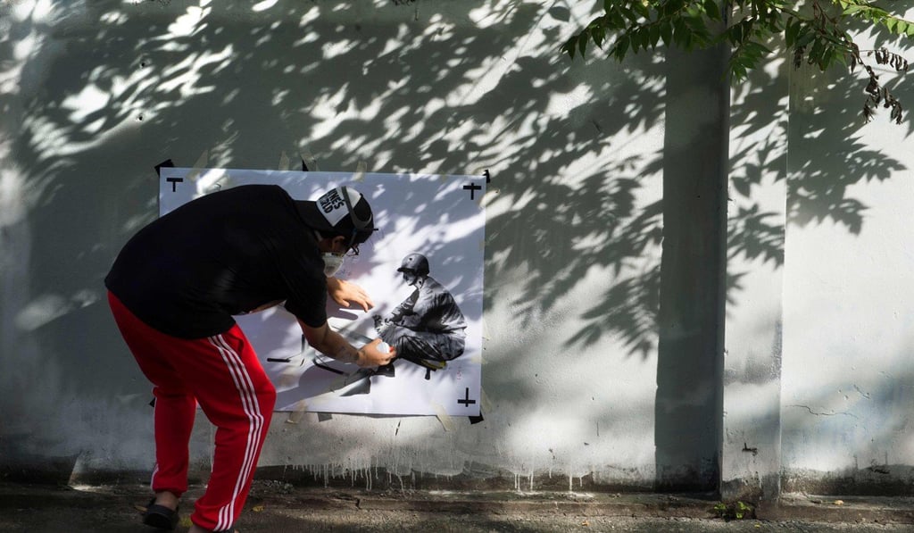 “Headache Stencil” spray-paints a fence in Bangkok. Photo: AFP
