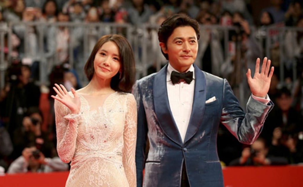 Singer Yoona of Girls’ Generation and actor Jang Dong-gun, co-hosts of last year’s Busan International Film Festival, wave to the crowd on the red carpet as they arrive at the event.