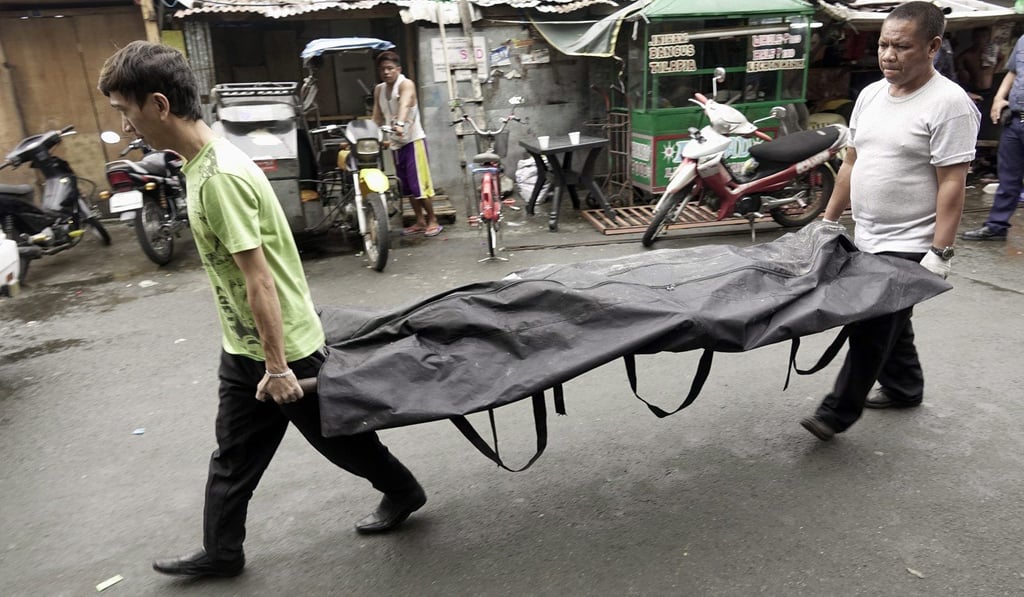 Filipino funeral parlor workers carry a body following a police operation against illegal drugs in Manila, Philippines in December 2016. Photo: EPA