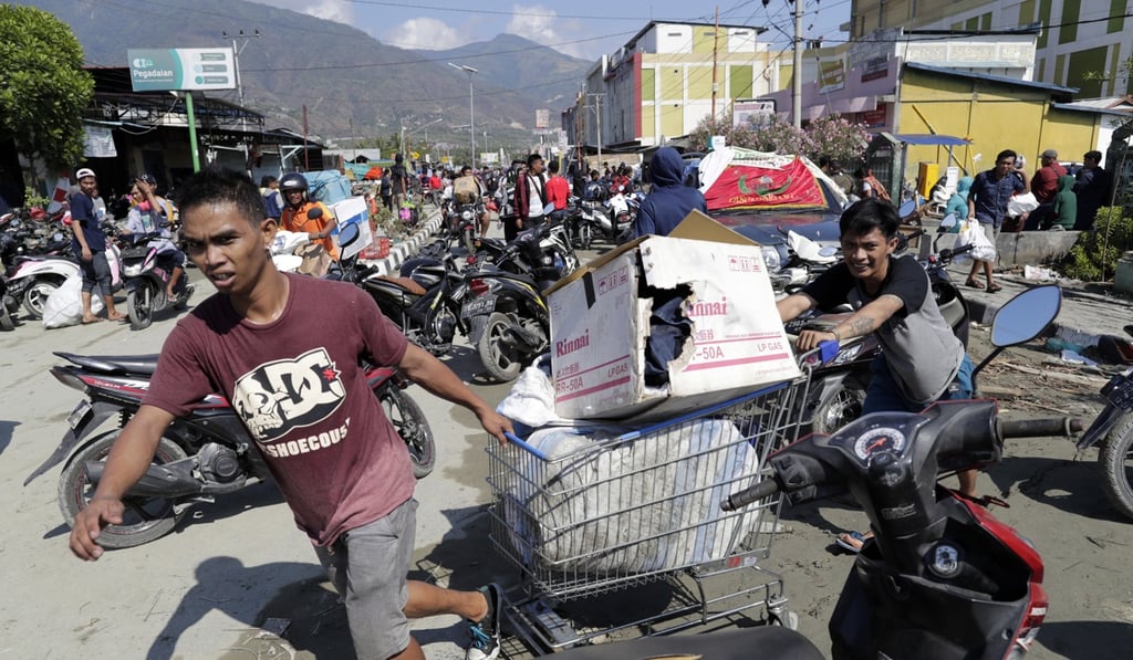 Men drag a shopping trolley with goods from a shopping centre in Palu. Photo: EPA Men drag a shopping trolley with goods from a shopping centre in Palu. Photo: EPA