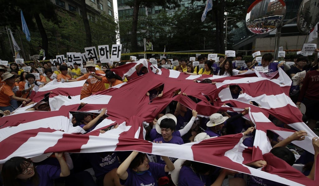 South Korean students tear a huge Japanese Rising Sun flag during a rally denouncing Japanese Prime Minister Shinzo Abe for failing to apologise for his country’s actions in the second world war. Photo: AP