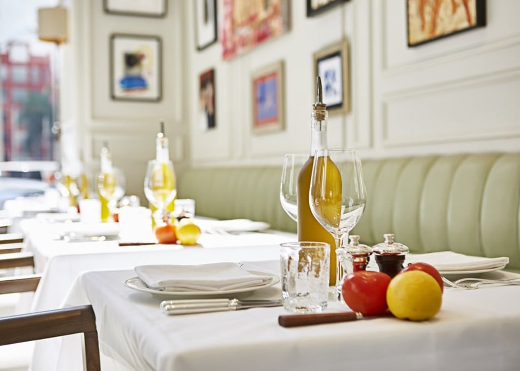Table settings at La Petite Maison. Natural light shines through the high ceiling.