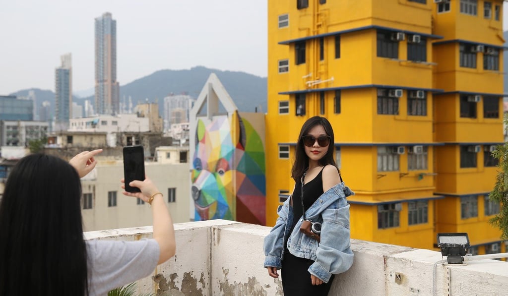 Tourist on a Sham Shui Po rooftop with “Rainbow Thief” in the background on the left. Photo: Sam Tsang