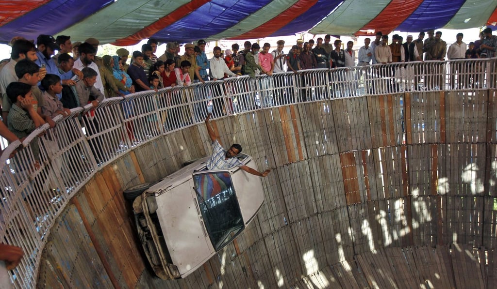 Mohammad Alishan, a performer from India’s eastern state of Jharkhand, performs a stunt as he drives a car on a ‘wall of death’ at a fair in Srinagar. Photo: Reuters