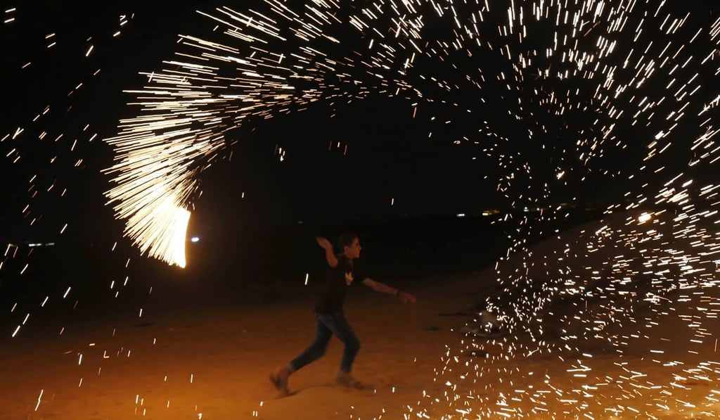 A Palestinian protester from a group calling themselves the “night confusion units” waves a sparkler near the Gaza-Israel border. Photo: AFP