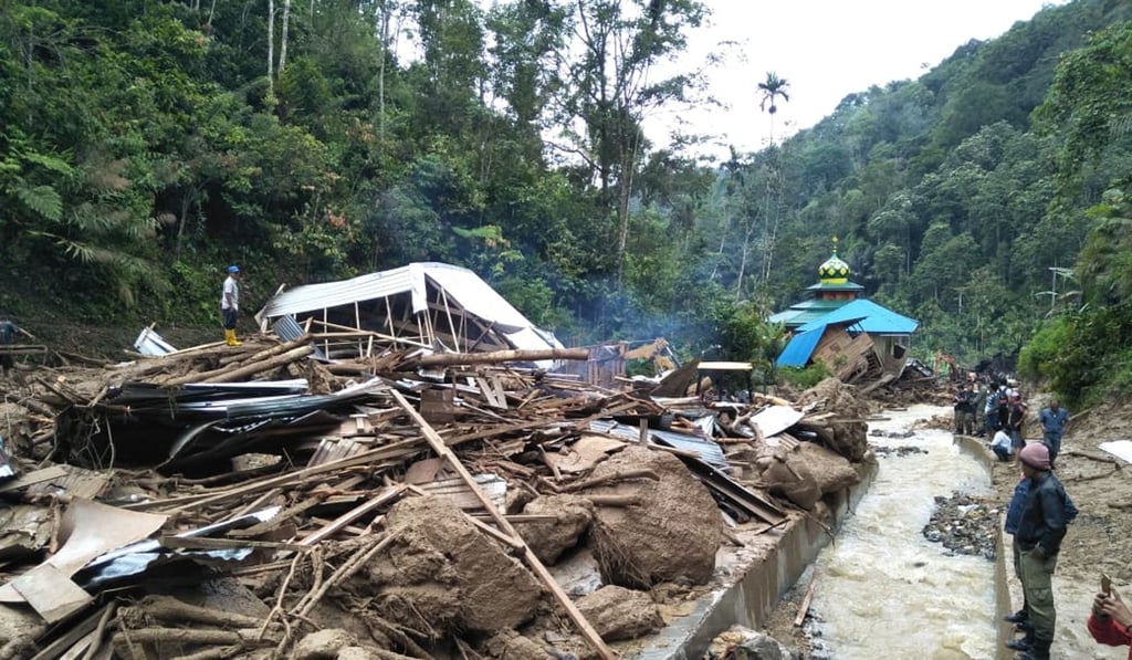 Villagers examine a site after it was hit by flash floods. Photo: AFP