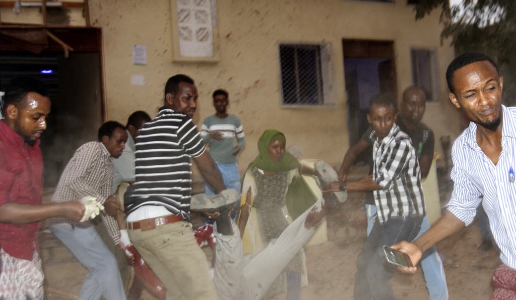 Bystanders helping a victim of Saturday’s attack in Somalia. Police said suicide bombers walked into the two locations in Baidoa and detonated their vests within minutes of each other. Photo: EPA-EFE