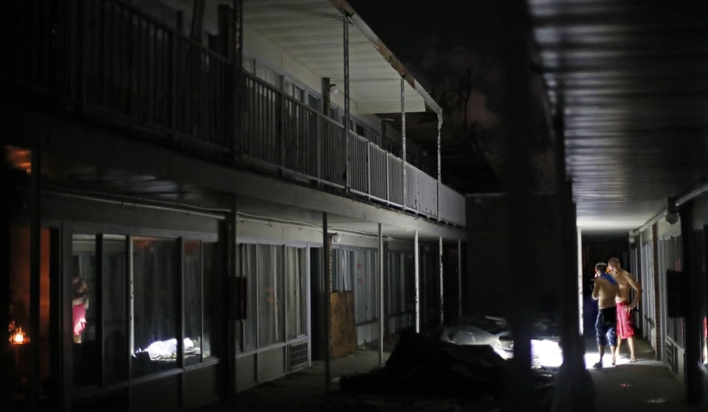 Residents use torches to navigate the dark walkways at night at the damaged American Quality Lodge after Hurricane Michael, in Panama City on October 16, 2018. Photo: AP