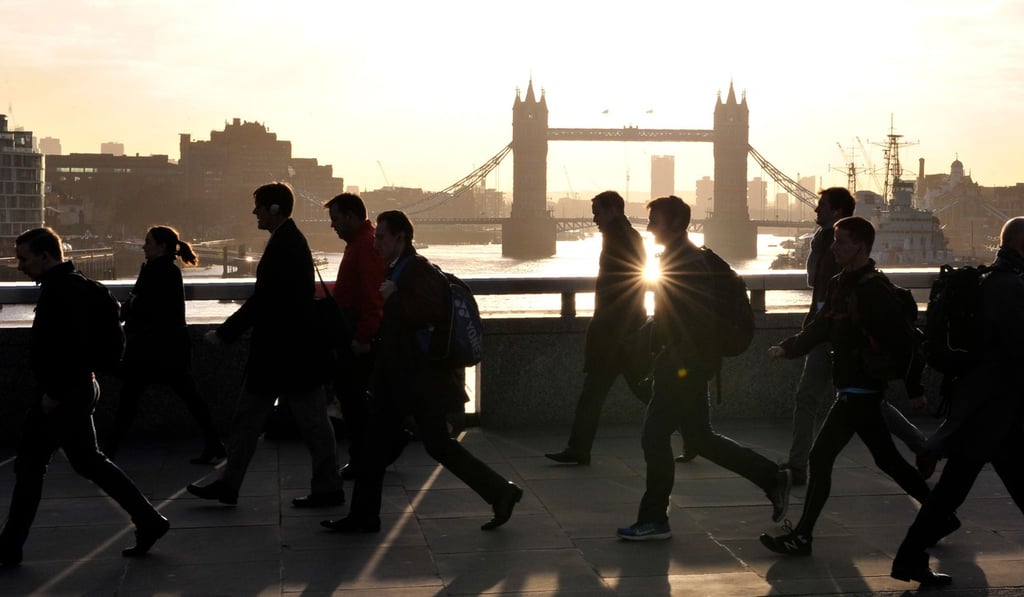 Morning commuters walk across London Bridge with Tower Bridge in the background into the City of London. Photo: AFP
