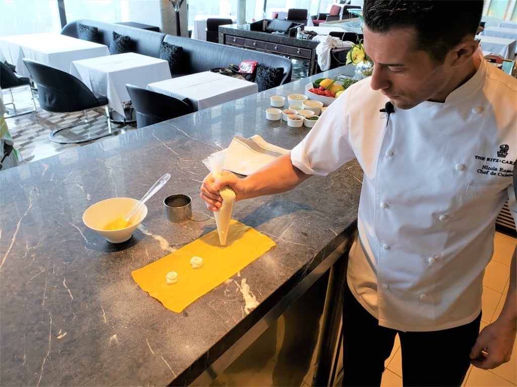 Chef Nicola Russo pipes the filling of the tortellini onto the pasta sheet.