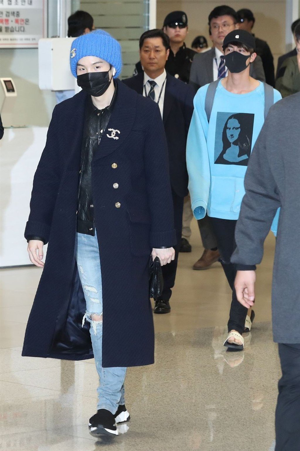 BTS members Suga (left), and Jin both wear face masks after the band’s arrival at Incheon International Airport on Tuesday.