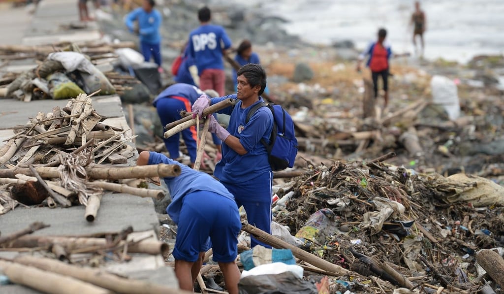 Workers remove debris washed ashore along the bay walk in Manila. Photo: AFP Workers remove debris washed ashore along the bay walk in Manila. Photo: AFP