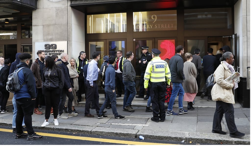 Police officers and security watch as people re-enter the building after the stabbing incident. Photo: AP Police officers and security watch as people re-enter the building after the stabbing incident. Photo: AP