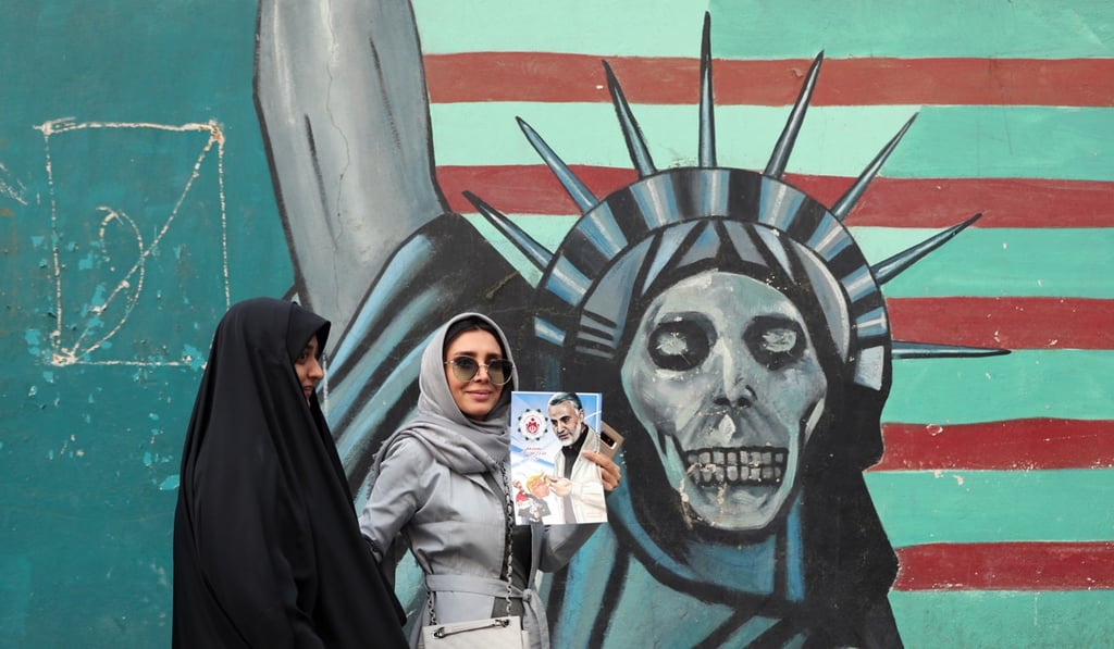 An Iranian woman walks past a mural depicting a skull-faced Statue of Liberty. Photo: EPA