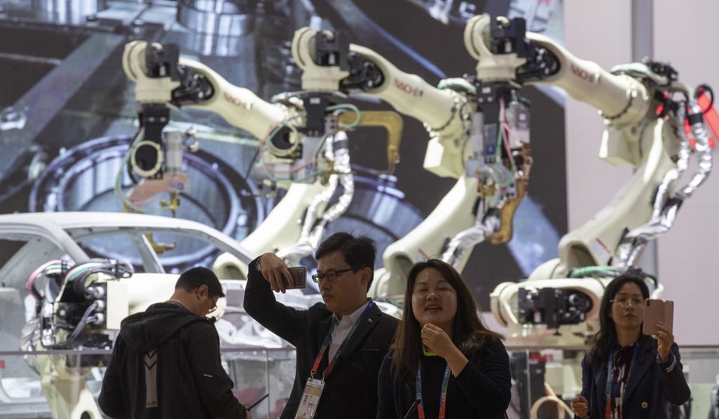 Expo attendees walk past robotic arms on display. Photo: AP