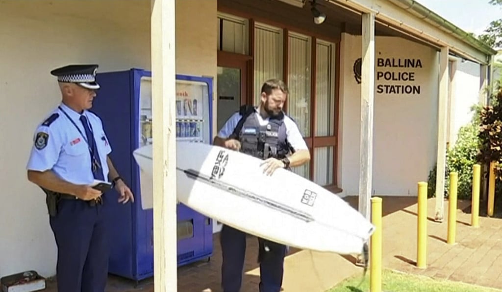 A police officer holds the surfboard that was used to fend off the shark. Photo: ABC/AP A police officer holds the surfboard that was used to fend off the shark. Photo: ABC/AP