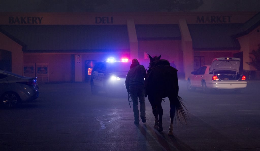 Hillery Johnson, who lost everything but the clothes on her back and her horse Augie, prepares to leave Augie in a shopping centre car park, after law enforcement officers said it was time to leave as the fire grew closer. Photo: EPA-EFE