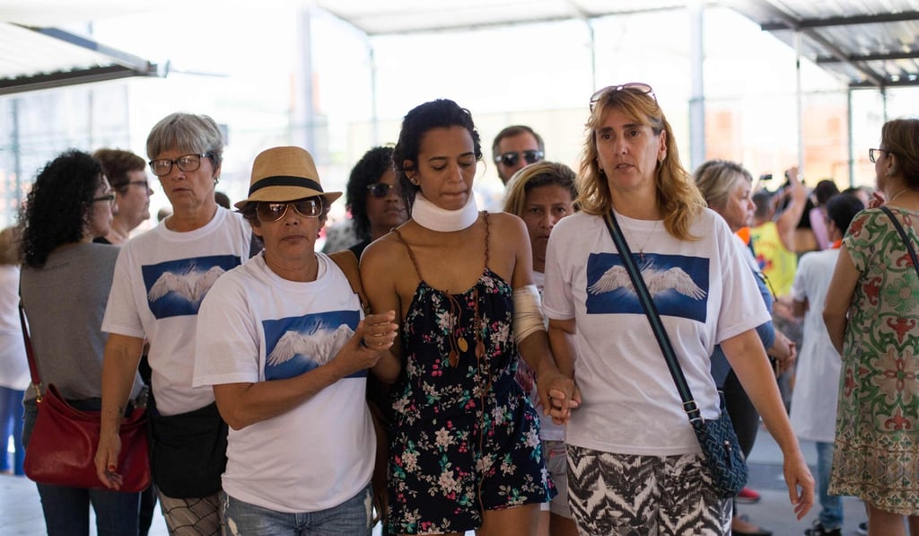 Brazilian Raquel Cavalcanti, one of the survivors of the landslide on the Morro da Boa Esperanca following heavy rains, receives help from volunteers at Municipal School Francisco Portugal Neves. Photo: AFP