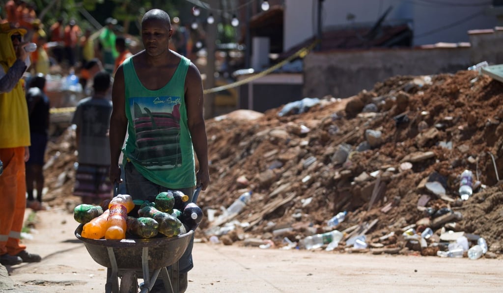 A man carries bottles of soft drinks after pulling them out of the rubble after the landslide. Photo: AFP