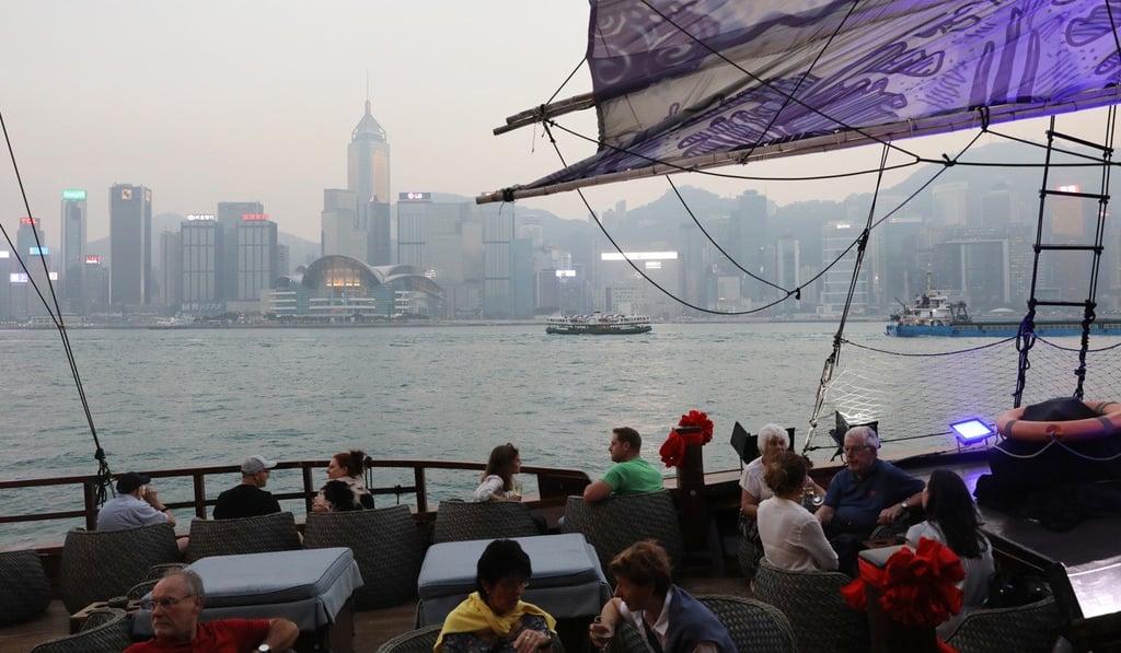 Tourists take a ride on a junk boat in Victoria Harbour as smog hangs over buildings in the background. Photo: Sam Tsang