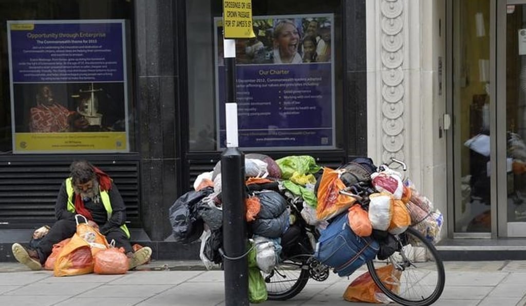 A homeless man next to his bicycle loaded with possessions on Pall Mall in London. Photo: Reuters
