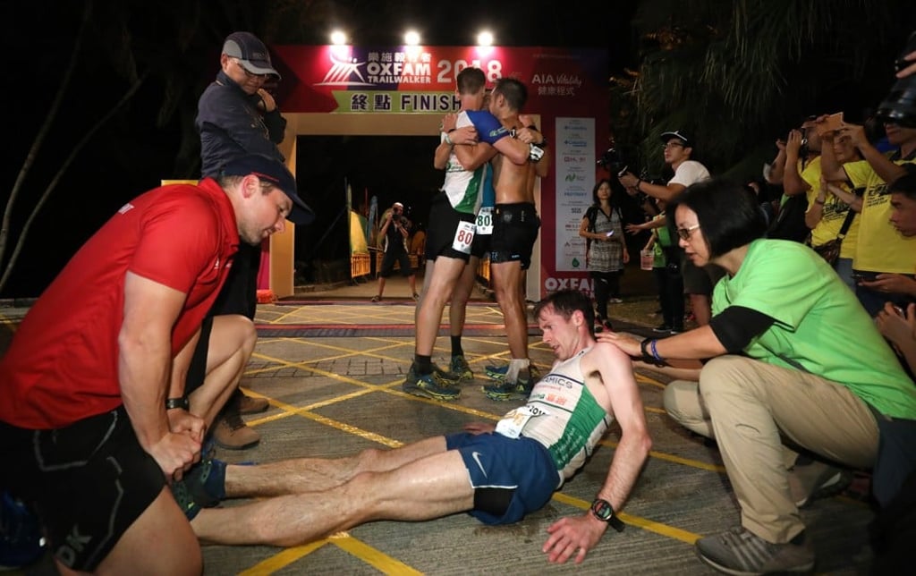 Jeff Campbell collapses on the finish line while his team celebrate behind him.