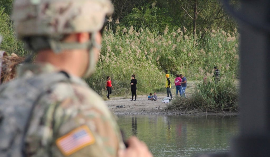 A US soldier looks across the Rio Grande from Laredo, Texas, into Nuevo Laredo, Mexico, where a group of people hang out on the river bank. Photo: AFP A US soldier looks across the Rio Grande from Laredo, Texas, into Nuevo Laredo, Mexico, where a group of people hang out on the river bank. Photo: AFP