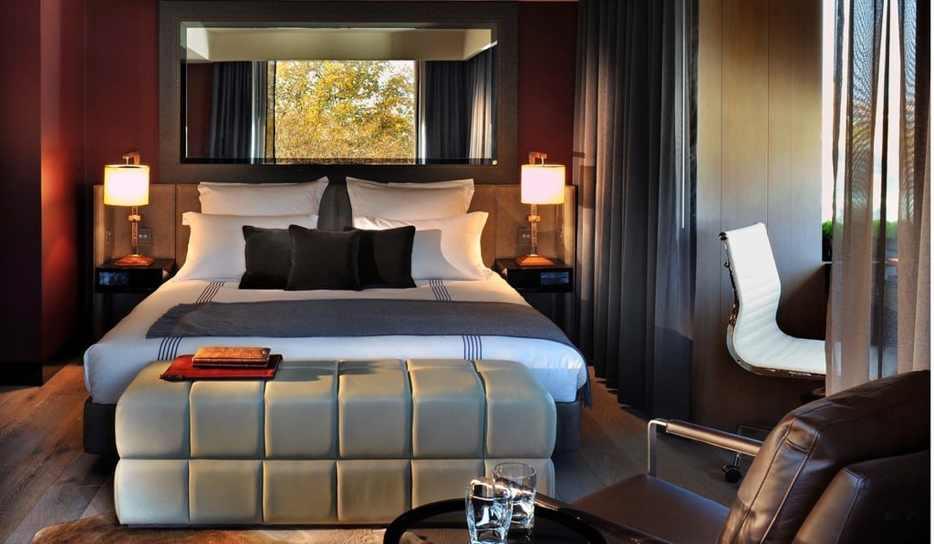 A large mirror above the bed reflects light and also creates a feeling of spaciousness in a bedroom at the boutique hotel, The Hari, in London,