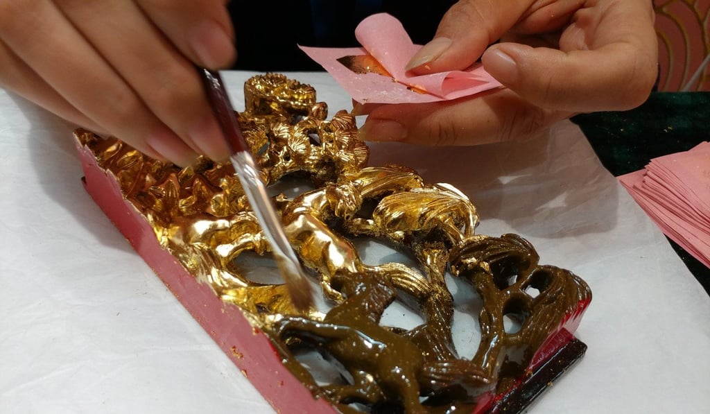 A Chaozhou craftsman adds a layer of gold to a piece of carved wood. Photo: Anven Wu