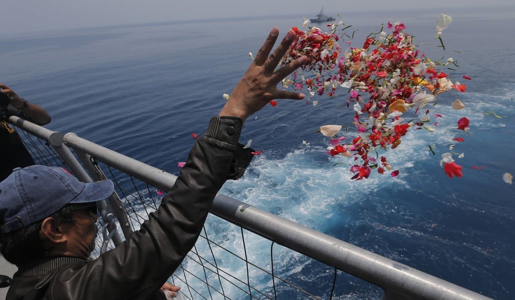 A relative sprinkles flowers for victims of the crash in the sea where it came down. Photo: AP