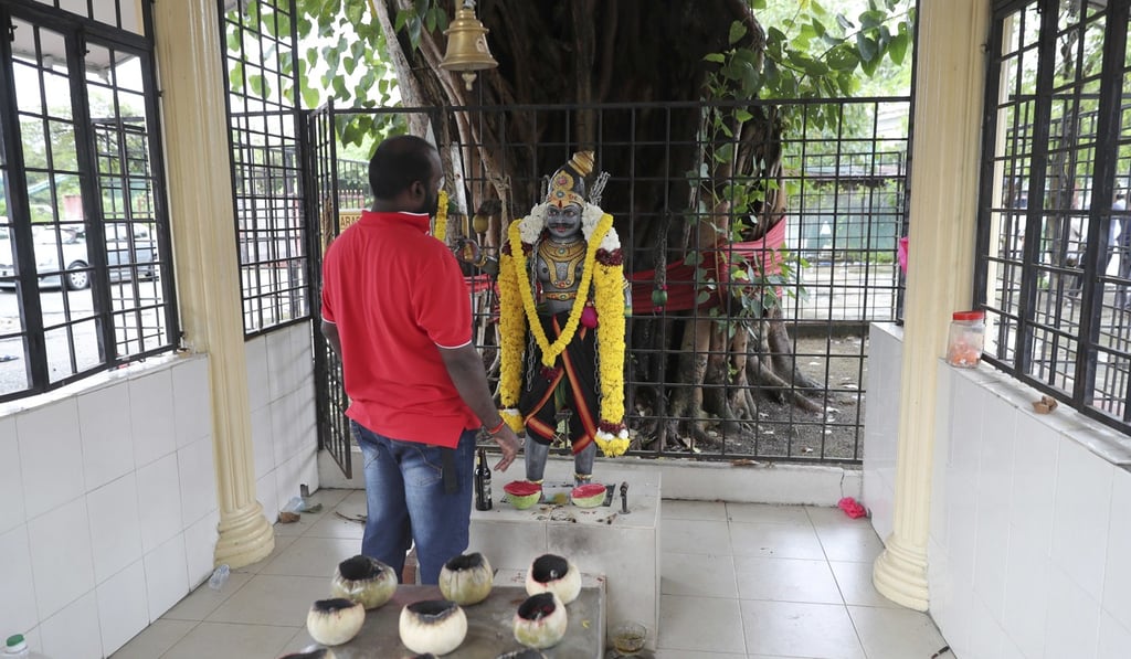 A man prays at the Sri Maha Mariamman temple after the riots that took place there earlier this week. Photo: AP A man prays at the Sri Maha Mariamman temple after the riots that took place there earlier this week. Photo: AP
