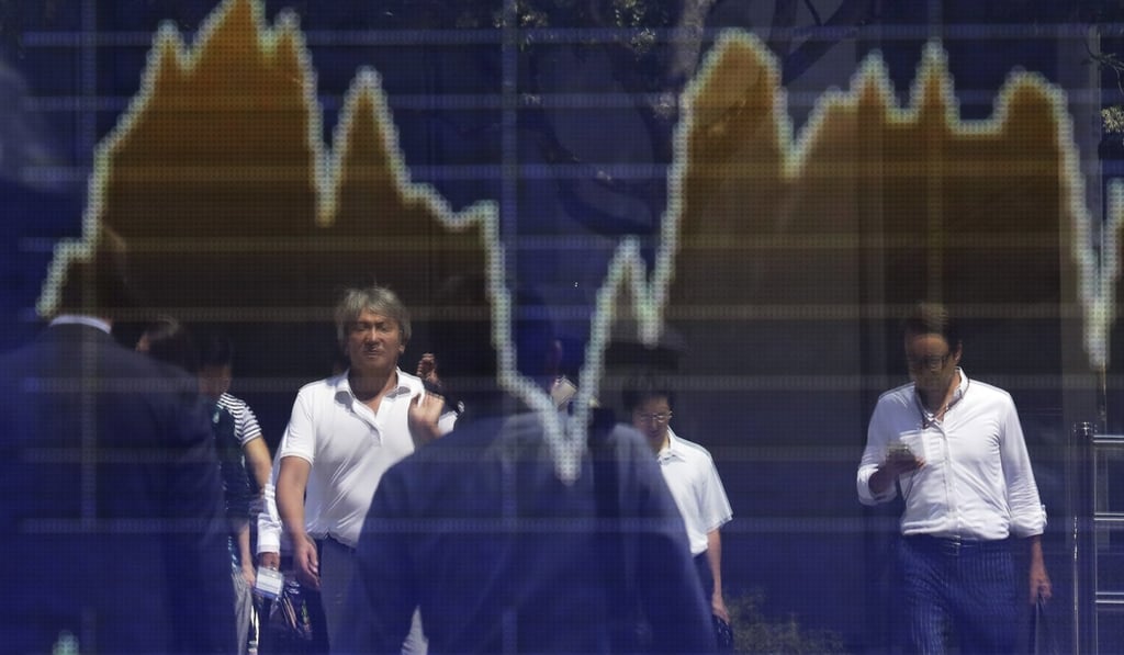 Pedestrians are reflected in a stock board in Tokyo. Countries with high savings rates, like Japan, also have higher debt-to-GDP ratios. A high debt-to-GDP ratio is not always a cause for alarm. Photo: Bloomberg